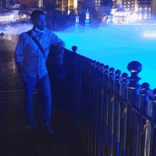 a man wearing a mask is standing next to a fence with a pool in the background that says kuala