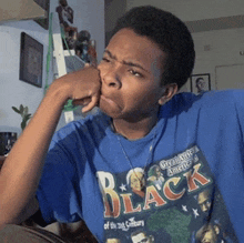 a young man wearing a blue shirt that says black on it