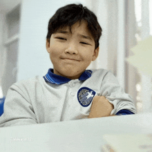 a young boy sitting at a table with a galaxy a32 in the background