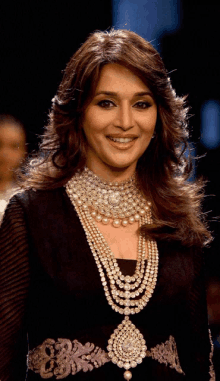 a woman wearing a necklace of pearls and diamonds smiles