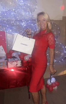 a woman in a red dress is holding a chanel shopping bag