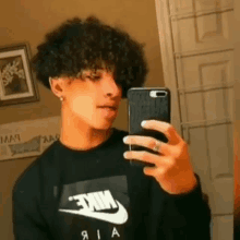 a young man is taking a selfie with his cell phone in a bathroom .