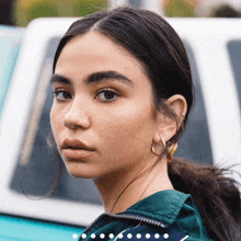 a woman wearing hoop earrings and a green jacket