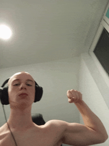 a shirtless man wearing headphones flexing his muscles