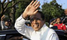 a man in a white shirt and glasses is waving his hand