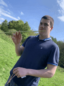 a man wearing a blue shirt with a bird on it is eating asparagus