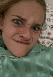 a woman making a funny face while laying in bed