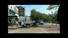 a group of people sit at a picnic table in front of a store that says ' abercrombie & fitch '