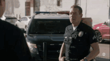 a police officer is standing in front of a police car and talking to another police officer