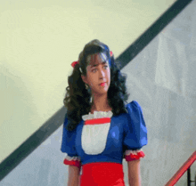 a woman in a blue red and white dress is standing on stairs