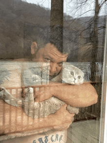 a man holding a cat with a tattoo on his arm that says eat cat