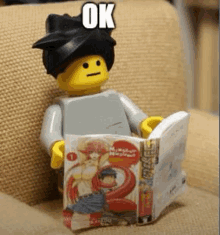 a lego man is reading a book while sitting on a couch .