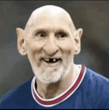 a bald man with a beard and big ears is wearing a blue shirt and smiling .