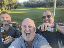 three men holding bottles of beer one of which says rh on it