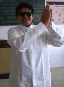 a boy wearing sunglasses and a white shirt stands in front of a chalkboard that says theme of the year