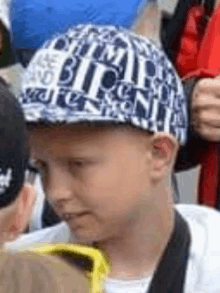 a young boy wearing a baseball cap with the word bitch on it .