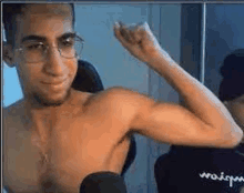 a shirtless man with glasses is flexing his muscles .