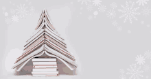 a stack of books shaped like a christmas tree with snowflakes in the background