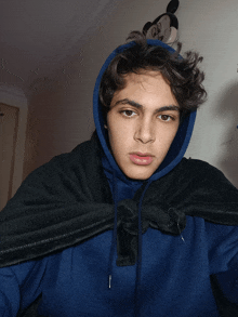 a young man wearing a blue hoodie and a black blanket