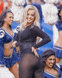 a cheerleader in a black jumpsuit holds a microphone