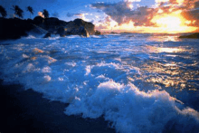 a sunset over the ocean with waves crashing on the shore .