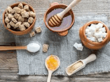 a wooden table topped with bowls of sugar and honey .