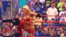 a woman in a bikini is wrestling a man in a wrestling ring in front of a crowd .