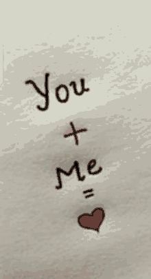 a piece of paper that says you + me with a red heart in the middle