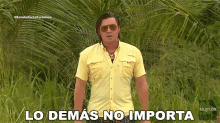 a man wearing sunglasses and a yellow shirt stands in a field with the words " lo demás no importa " written below him