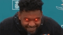 a man with red eyes is looking at the camera .