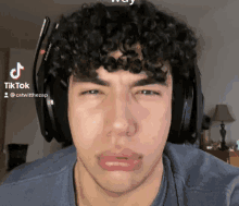 a man with curly hair wearing headphones and a tiktok logo on his face