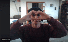 a man is making a heart shape with his hands and the name platonass is visible in the corner