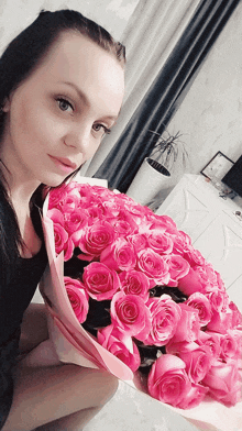 a woman holds a large bouquet of pink roses in her lap