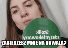 a woman blowing a kiss while holding a sign that says " zabierzesz mnie na drwala "