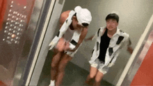 two men dressed in cow costume are standing in an elevator .