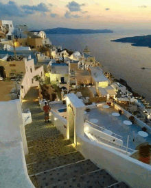 a man stands on a balcony overlooking a city with a sign that says ' athens ' on it