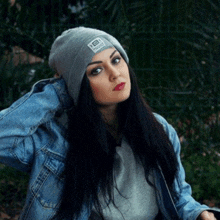 a woman wearing a denim jacket and a grey beanie with a sticker on it that says ' sbt '