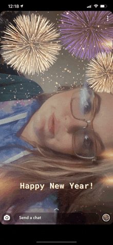 a woman with glasses is laying down with fireworks in the background