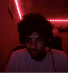 a man wearing headphones looks at the camera with a red background