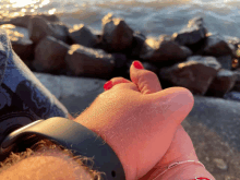 a close up of a person 's hand with red nails and a black watch