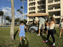 a group of children are standing around a golf cart