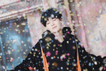 a person with their eyes closed is surrounded by confetti with the letters bts on the bottom right