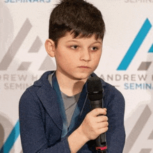 a young boy is holding a microphone in his hand and wearing a medal around his neck .