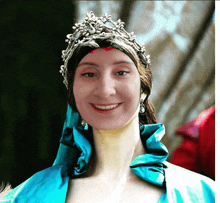 a woman wearing a blue dress and a silver tiara smiles for the camera