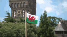 a flag with a red dragon on it is flying in front of a building with a clock on it