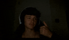 a young man wearing headphones gives a thumbs up