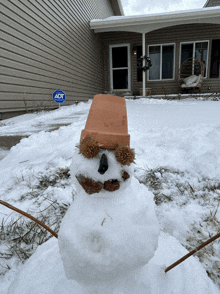 a snowman in front of a house with a sign that says adt on it