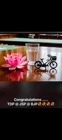 congratulations tdp @jsp @bjp with a glass of water and a bicycle on a table