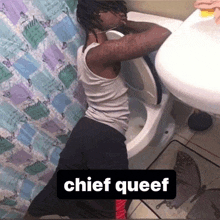 a man is sitting on a toilet in a bathroom with the words `` chief queef '' above him .