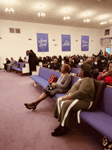 a group of people are sitting in a church with a banner that says jesus loves